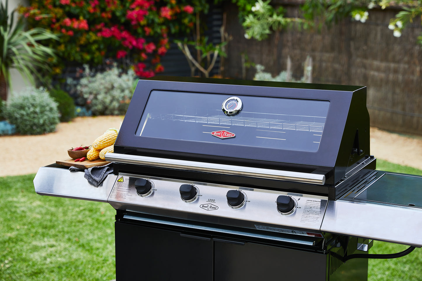 Beefeater 1200E Series 4 Burner Gas BBQ with Trolley and Side Burner in a garden with the hood closed close picture