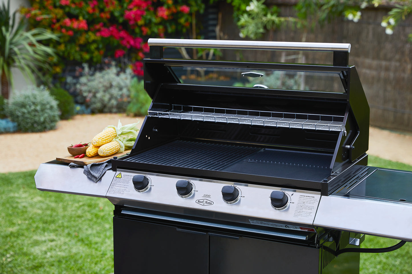 Beefeater 1200E Series 4 Burner Gas BBQ with Trolley and Side Burner in a garden with the hood open close picture 